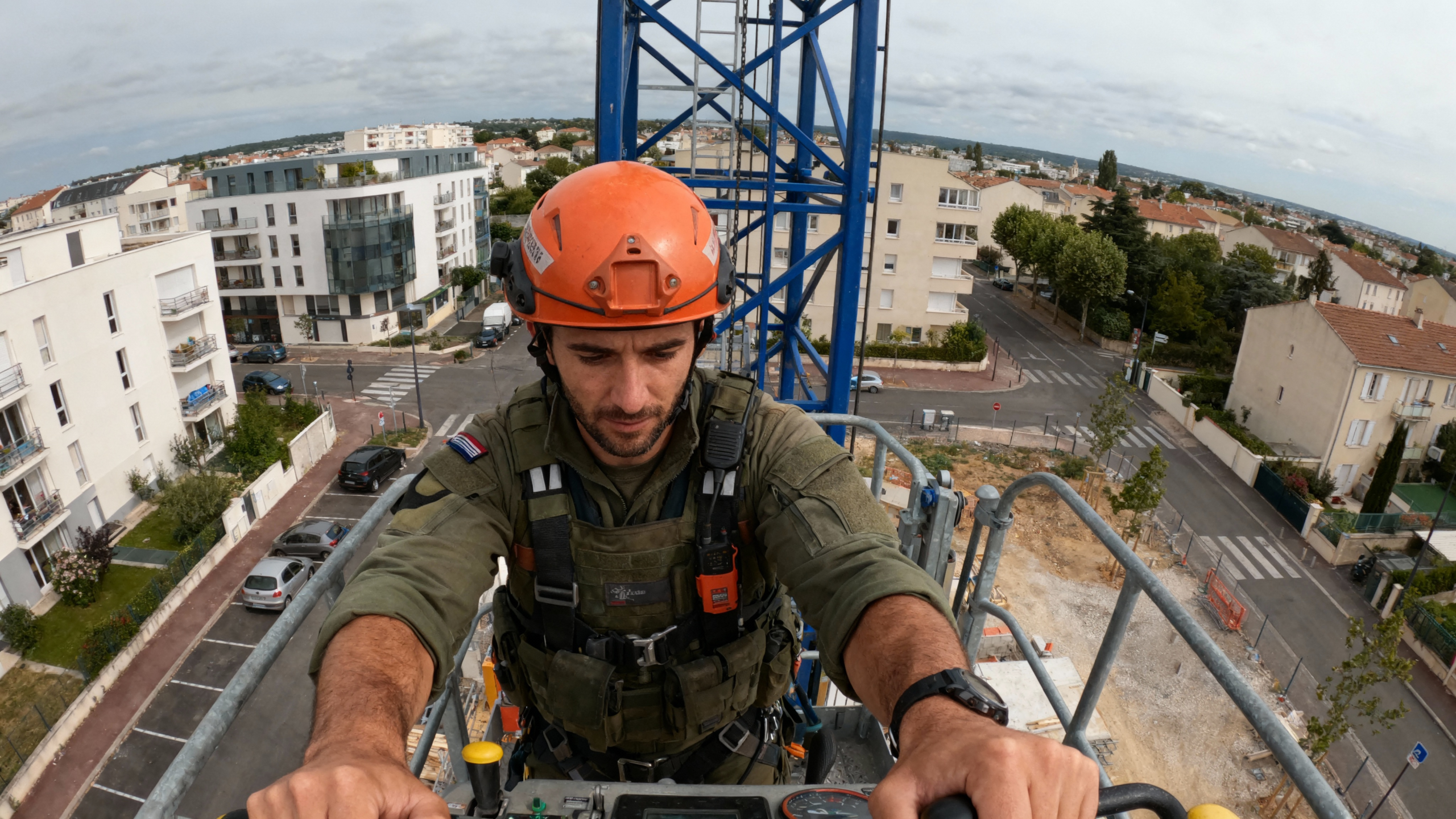 pexels-michal-pech-213601-757318 (1) Un homme en combinaison de travail et casque orange, contrĂ´lant une grue, surplombe un quartier urbain en construction.