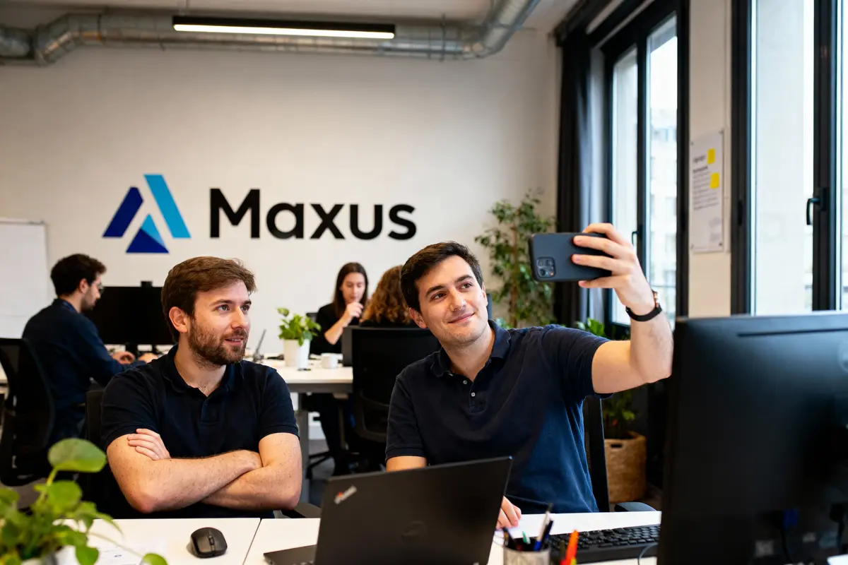 pexels-michal-pech-213601-757318 (1) Deux hommes au bureau Maxus, l'un prenant un selfie, ambiance de travail détendue.
