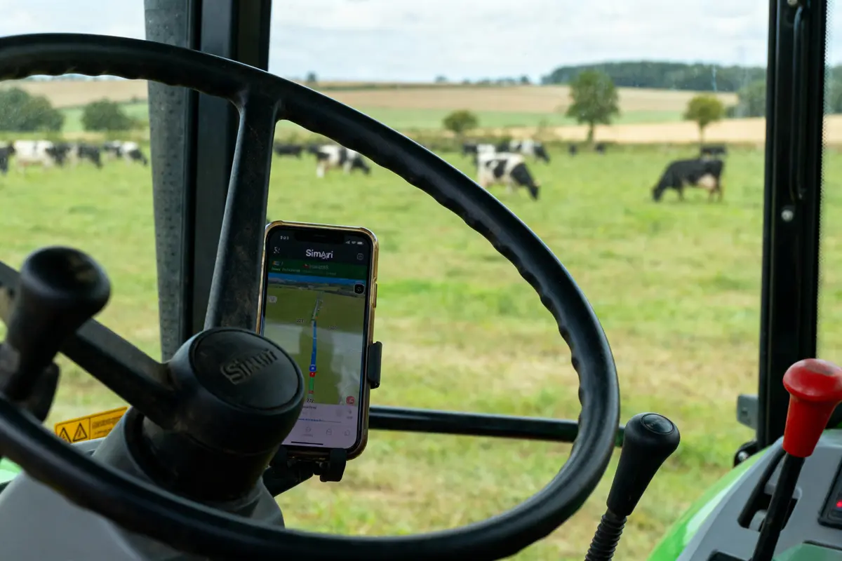 pexels-michal-pech-213601-757318 (1) Vue intérieure d'un tracteur avec volant, smartphone, et vaches dans un champ en arrière-plan.