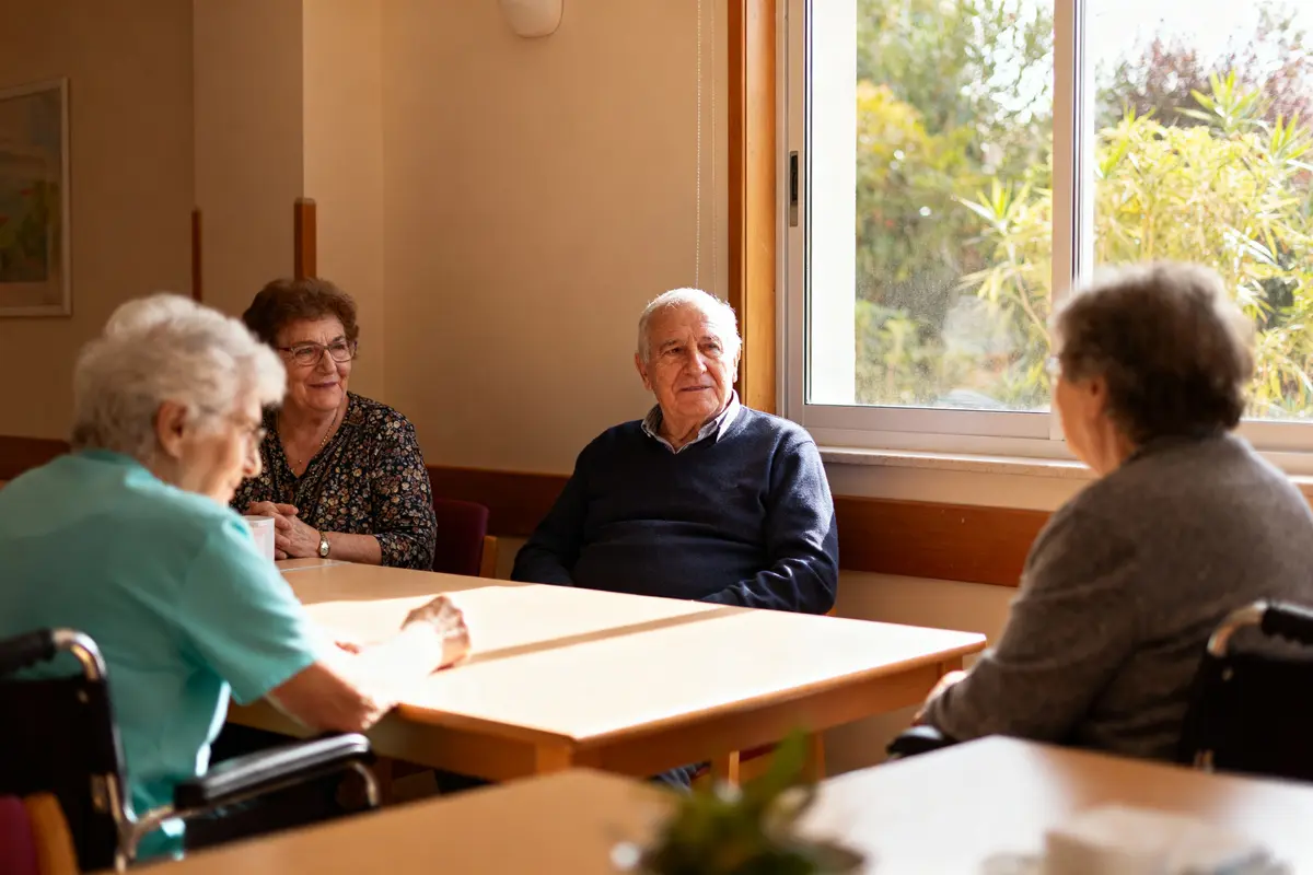 pexels-michal-pech-213601-757318 (1) Quatre personnes âgées assises autour d'une table, discutant dans une salle lumineuse près d'une fenêtre.