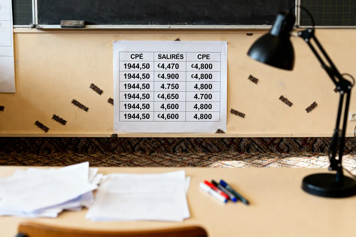 Tableau de salaires fixé au mur, avec documents et stylos sur le bureau.